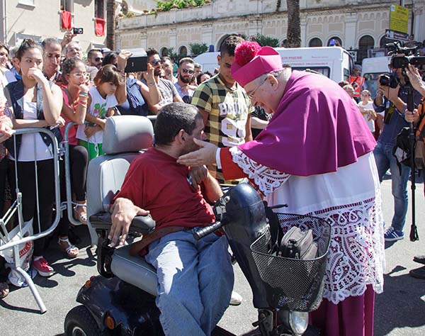 Mons. Morosini, Arcivescovo di Reggio Calabria, saluta un disabile durante la processione della Madonna della Consolazione